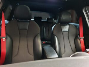 Interieur van een auto met gepersonaliseerde, rode gordels.