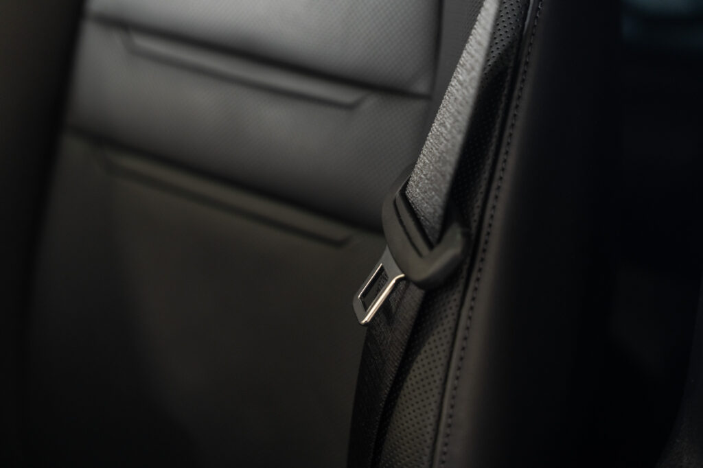 Zwarte autogordel bevestigd aan een leren autostoel in een luxe voertuiginterieur.