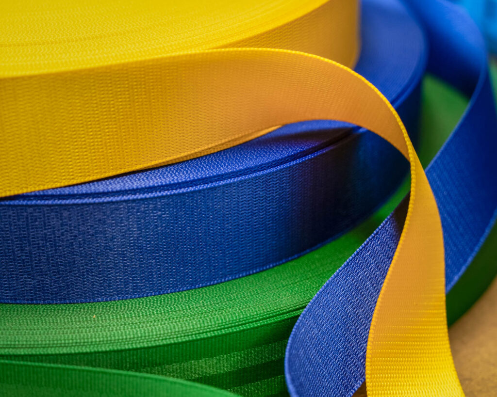 Gele, blauwe en groene rollen autogordelband op een werktafel, klaar voor verwerking of montage.