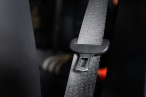 Close-up van een autogordel in een auto, toont de stof en sluiting voor inspectie op slijtage.