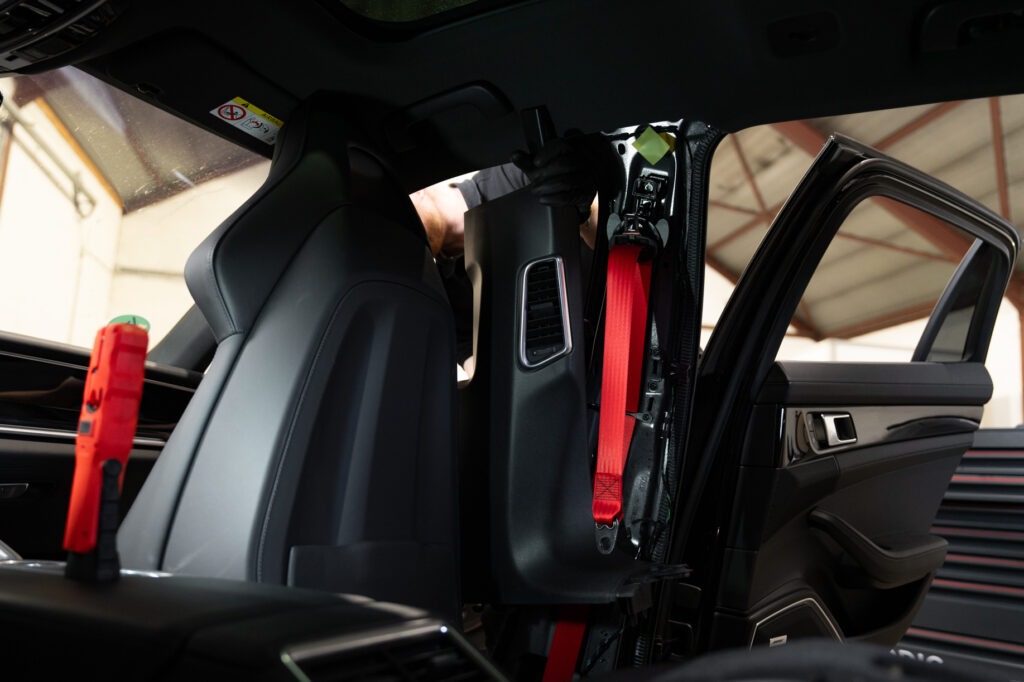 Rode autogordel gemonteerd in de B-stijl van een auto tijdens vervanging of installatie in de werkplaats.