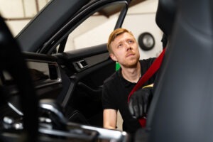 Monteur van Autogordel.nl test een rode autogordel in een auto om te controleren of de gordel soepel oprolt.