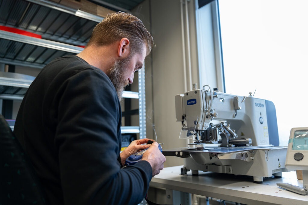 Specialist van Autogordel.nl werkt een custom BMW M-stijl autogordel af met professionele apparatuur in de werkplaats.